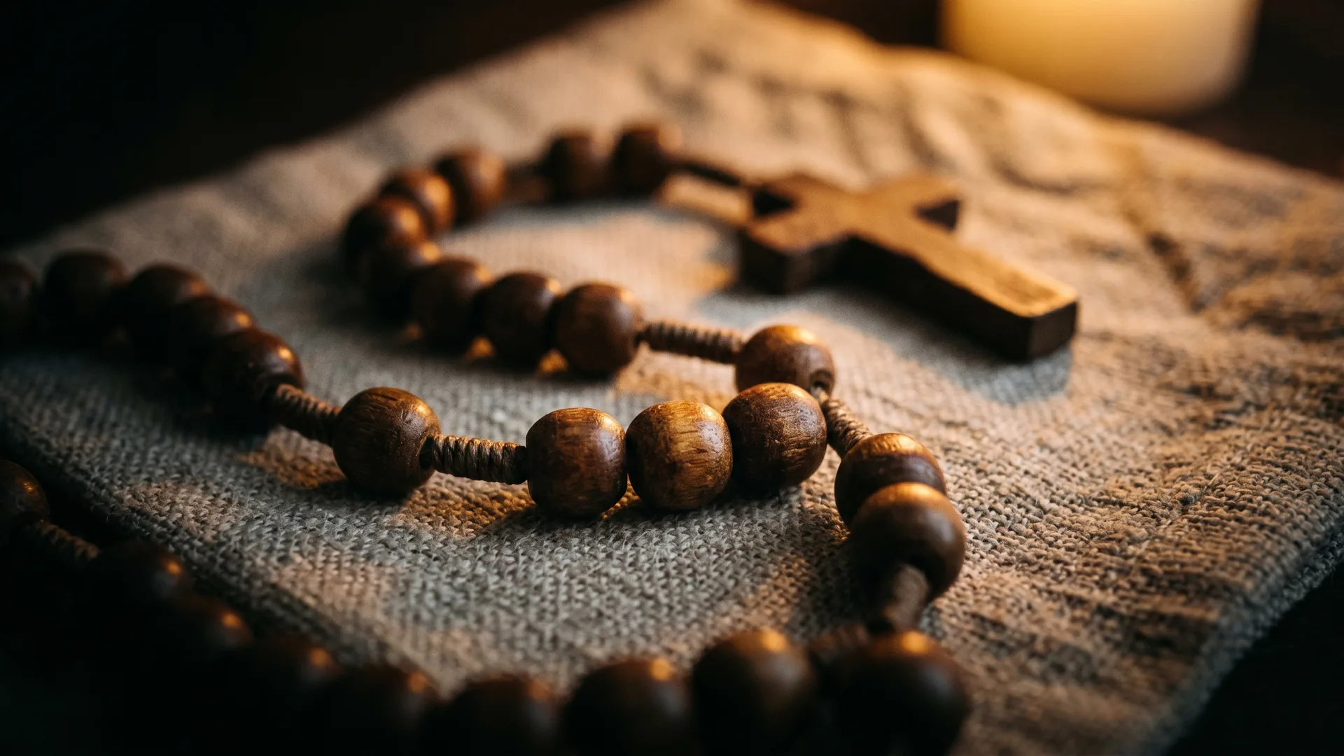 Wooden rosary beads resting in candlelight
